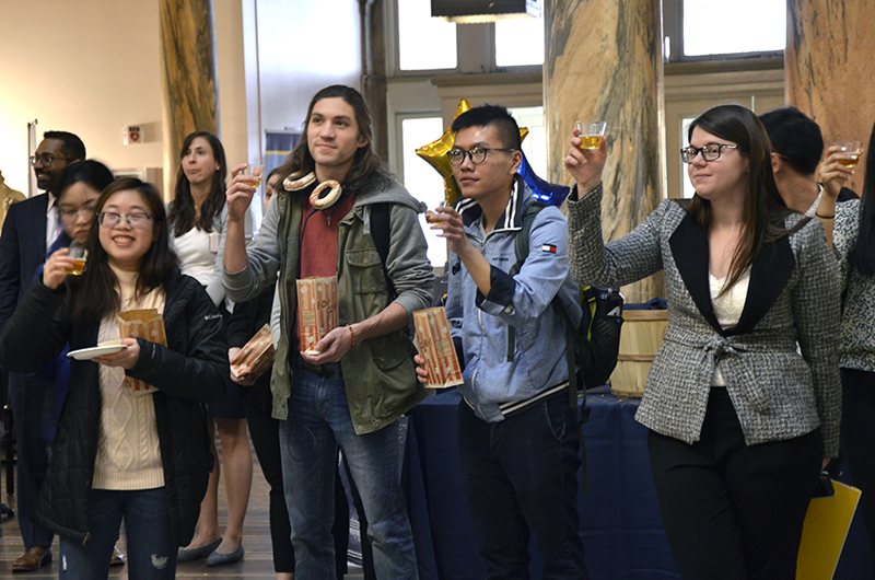 Ryan Barrett (middle left) and his friend Phu Phan (middle right) join in a celebratory toast at Drexel University's Co-op Send-off event alongside fellow students, faculty and staff.
