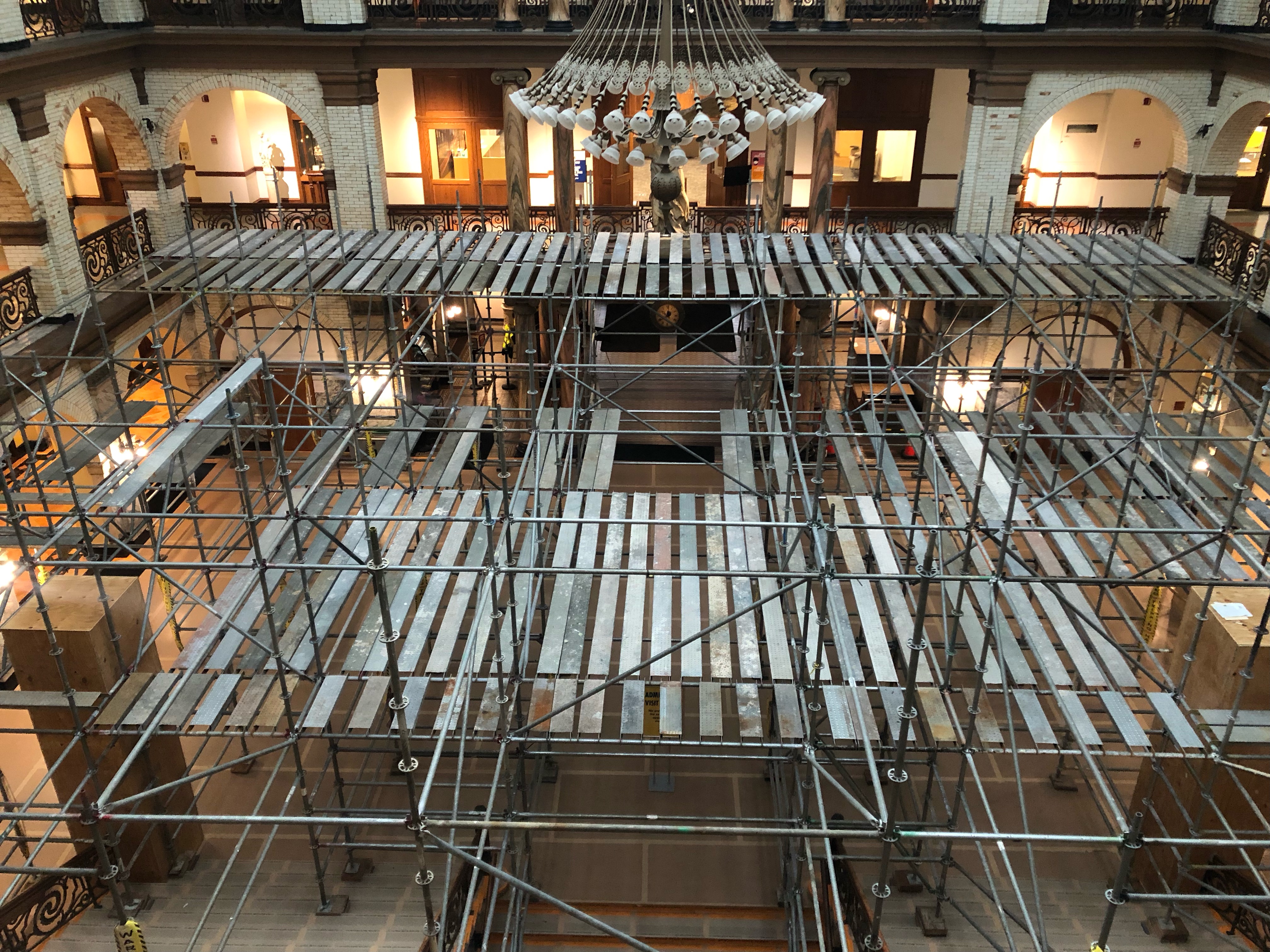 The second floor of scaffolding, as depicted on Nov. 15, 2021. Note the candelabra covered through the tall wooden boxes and the gray floor covering the marble staircase and tiled court.
