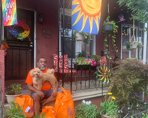 Jeffrey Jordan on his porch with his dog, Justice, surrounded by supplies to distribute to the West Philadelphia Promise Neighborhood.