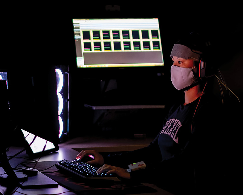 person wearing a mask and using the computer