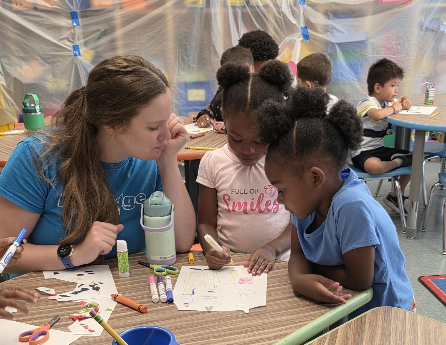 A Drexel student teacher works with two children on a drawing during the Kindergarten Bridge program.