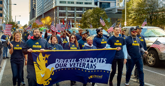 Drexel Dragons at the Veterans Parade Holding a Drexel Supports Our Veterans Banner
