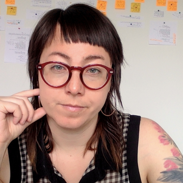 Woman with red glasses behind white board. 