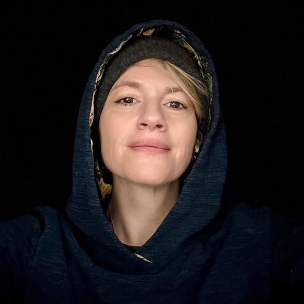 A woman with hood up and black background