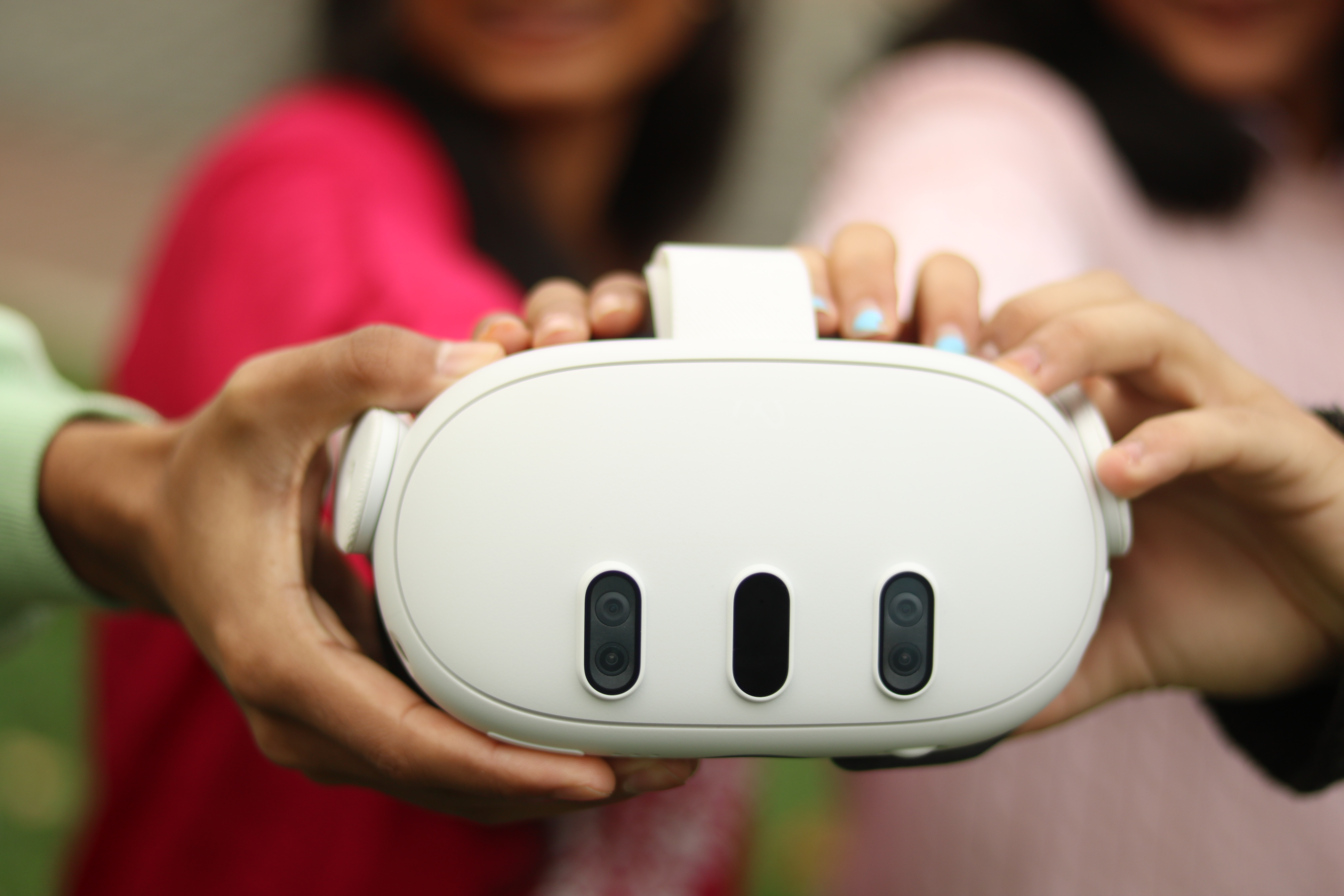 A VR headset, held by four sets of hands