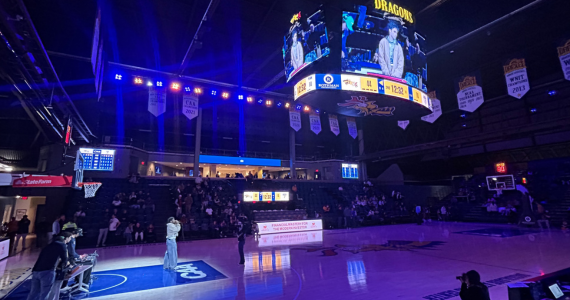 basketball gym during halftime show, dimmly lit with spot light on music performer on the floor in the paint