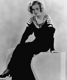 Black and White Photograph of Garbo in Black Dress and Heels sitting down