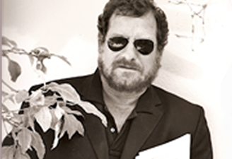 Black and White Photograph of Rosenman with sunglasses on and script in hand