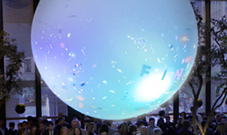 Blue lighted ball above party crowd with digital confetti