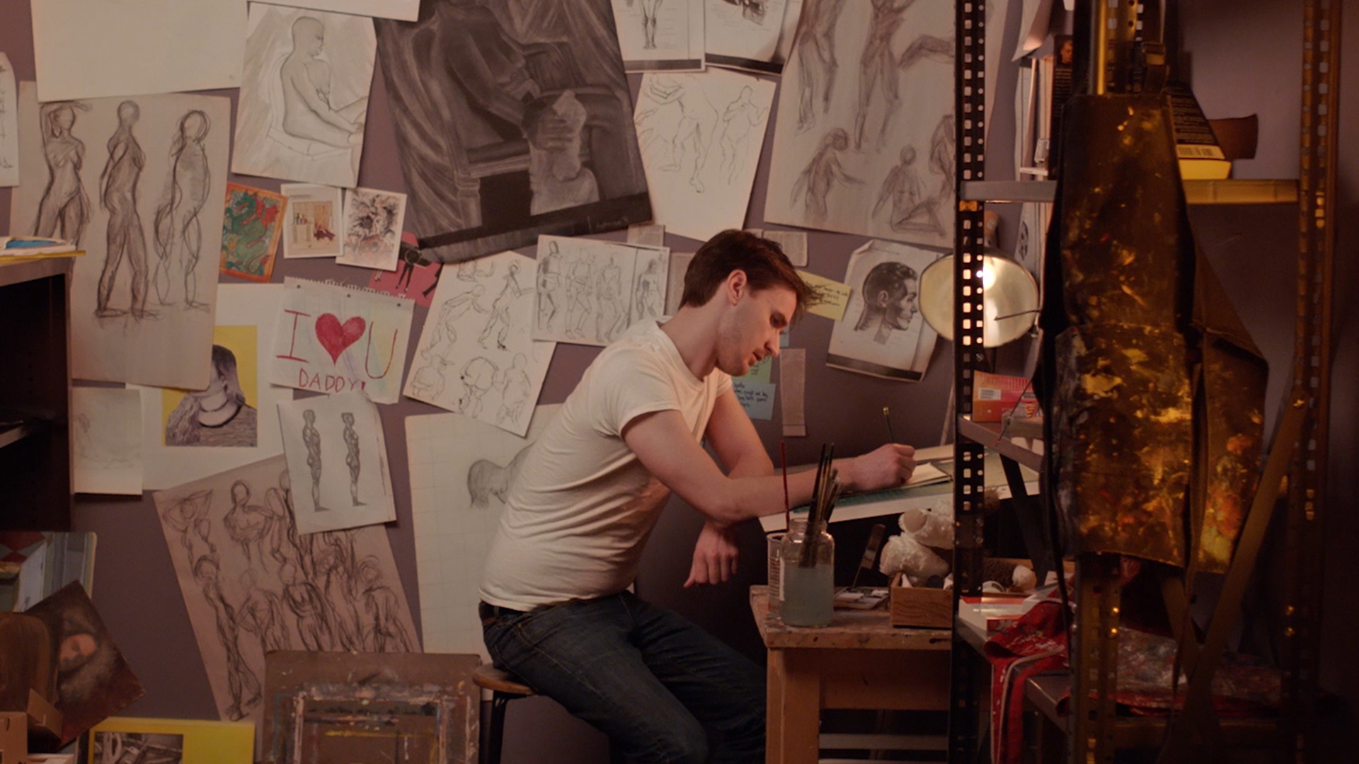 A man sits at a table surrounded by art