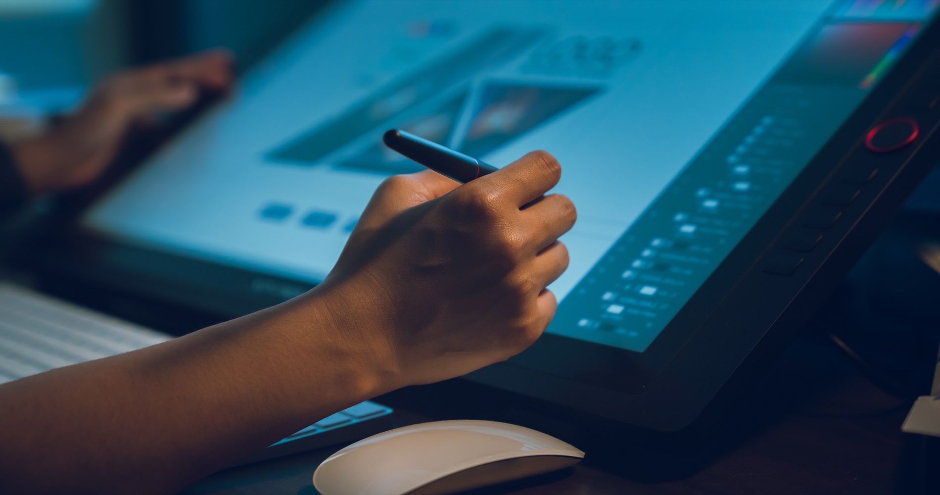 Hand using a stylus on a pen-display monitor to edit a digital design.